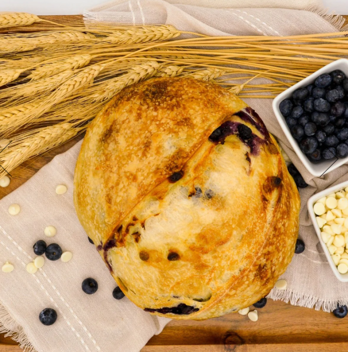 lemon blueberry sourdough bread with cups of blueberries and white chocolate chips to the side